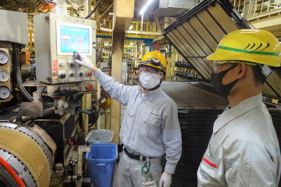 タイヤ成型工程で新人指導をする山田さん（左）