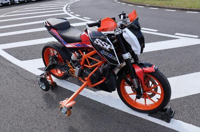 SSPの名前の由来となった二輪車の車体を支えるオレンジ色と黒色の小さな車輪がついた”サイドスタンド”SSPでは、このサイドスタンドの代わりにボランティアの方々がパラモトライダーを支えている