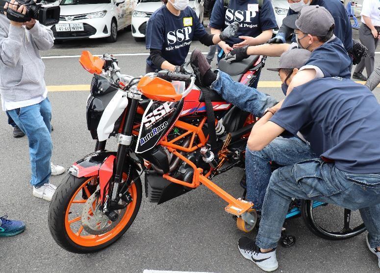 パラモトライダーがバイクにまたがれるよう、2、3人のボランティアがサポートをすることも